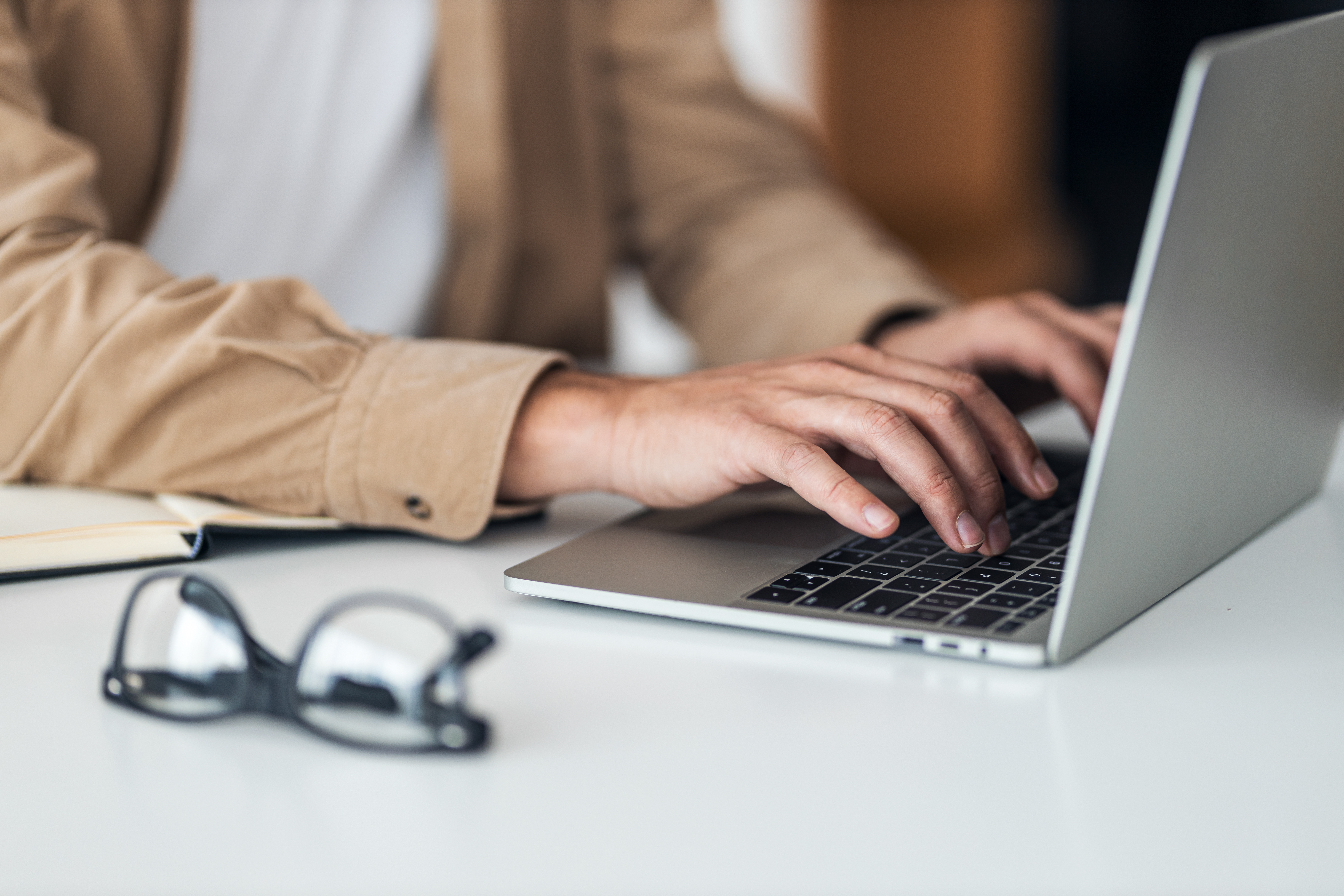 Close up of mans hands typing on laptop. local insurance agency.